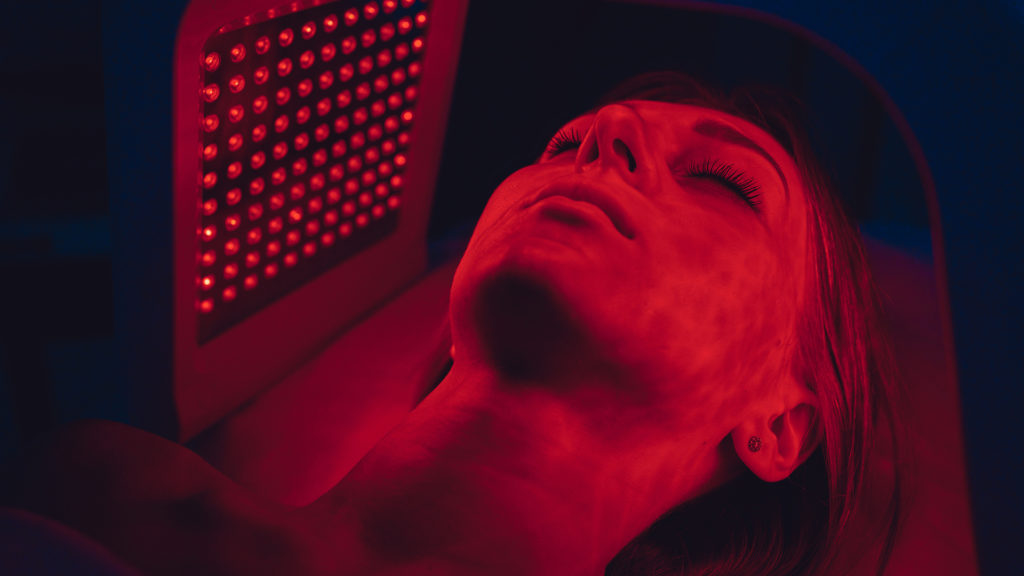 LED red light is treating the facial skin of a young woman.