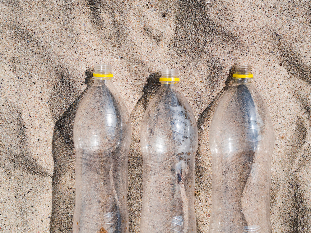three-empty-plastic-bottle-arrange-row-sand-3
